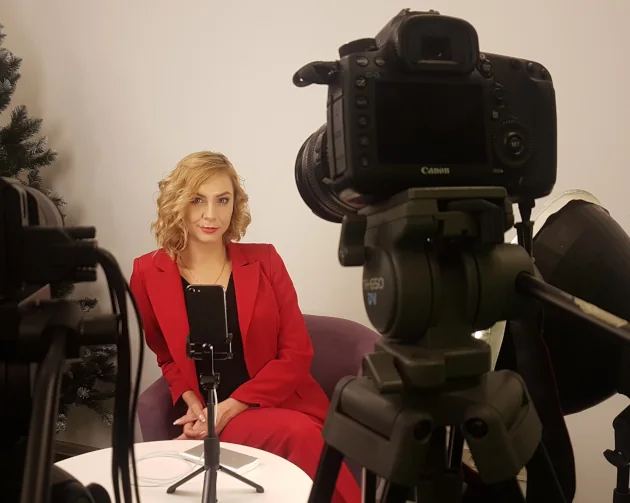 Valerie Ve seated in front of a camera and lights during a video recording