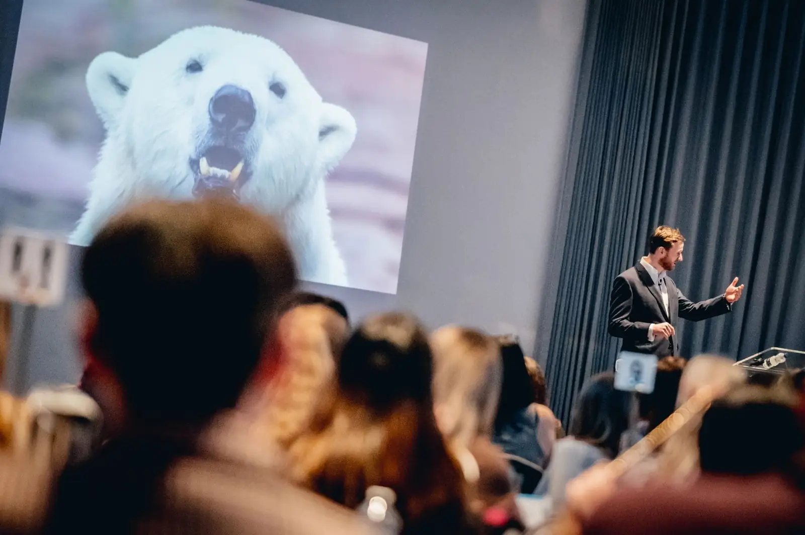 An audience watching a keynote speaker in a darkened conference auditorium